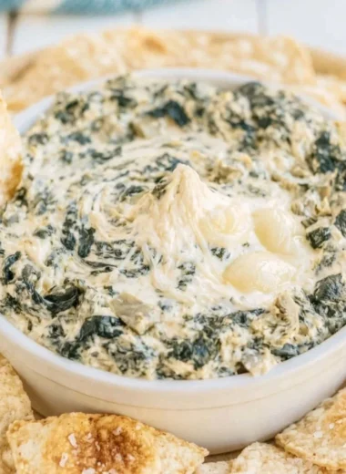 Creamy slow cooker spinach artichoke dip served in a bowl with chips