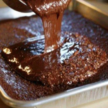 Cozy warm chocolate sheet cake topped with creamy frosting on a wooden table
