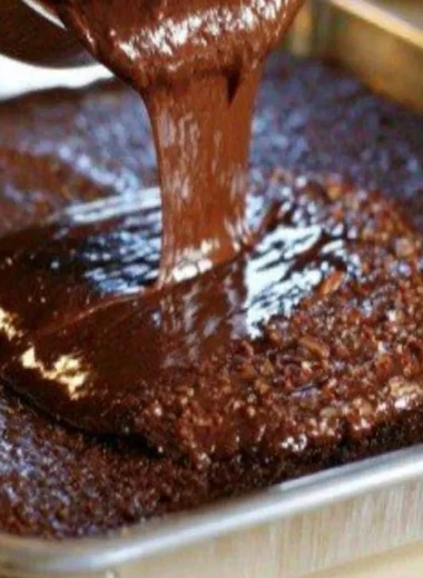 Cozy warm chocolate sheet cake topped with creamy frosting on a wooden table