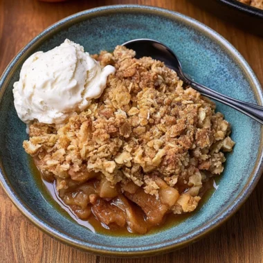 Delicious cast iron apple crisp served with a scoop of vanilla ice cream