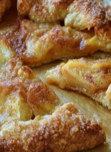 Slice of delicious rustic French apple tart with fresh apples on a wooden table