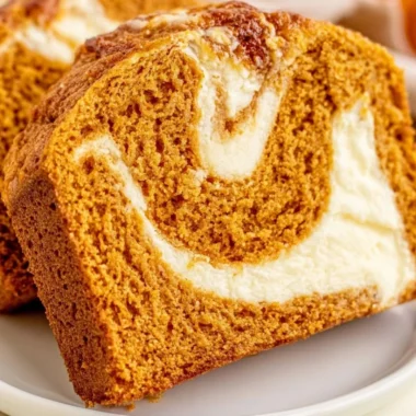 Delicious pumpkin bread topped with cream cheese frosting on a wooden table
