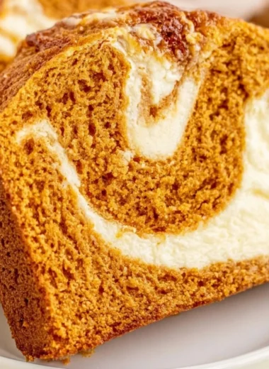 Delicious pumpkin bread topped with cream cheese frosting on a wooden table
