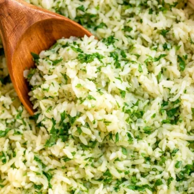 Bowl of cozy cilantro lime rice garnished with fresh cilantro and lime wedges.