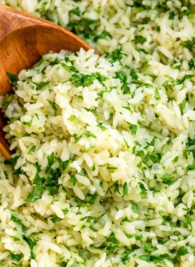 Bowl of cozy cilantro lime rice garnished with fresh cilantro and lime wedges.