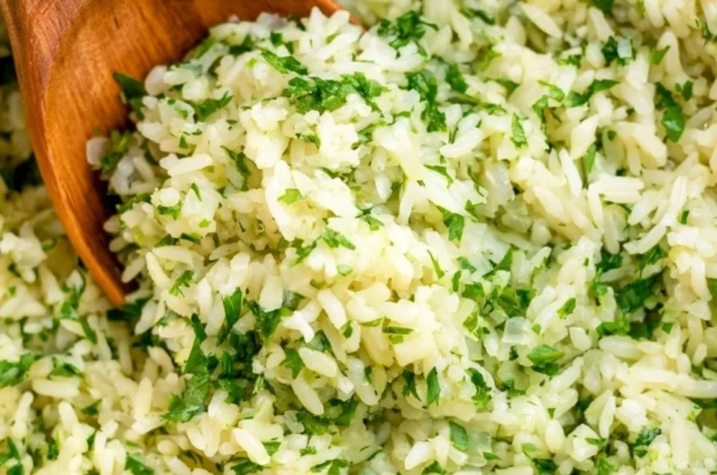 Bowl of cozy cilantro lime rice garnished with fresh cilantro and lime wedges.