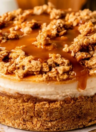 Slice of cozy apple crumble cheesecake topped with cinnamon and apples