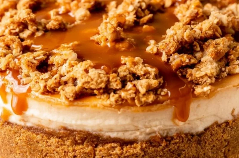 Slice of cozy apple crumble cheesecake topped with cinnamon and apples