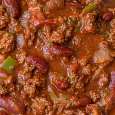 Bowl of cozy easy chili recipe topped with cheese and herbs