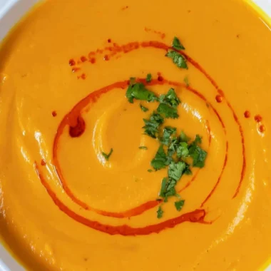 Bowl of cozy sweet potato soup topped with fresh herbs