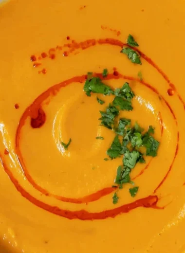 Bowl of cozy sweet potato soup topped with fresh herbs