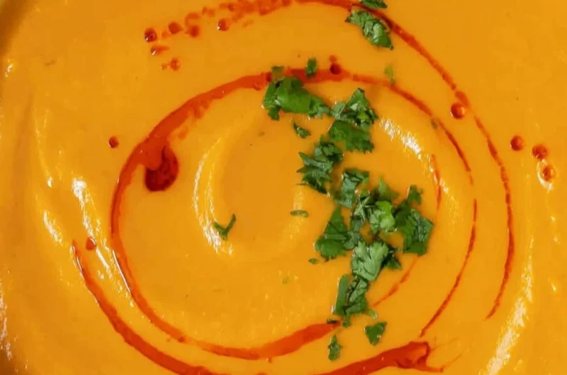 Bowl of cozy sweet potato soup topped with fresh herbs