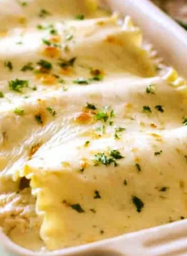 Creamy Chicken Alfredo Roll Ups served on a plate, topped with parsley.