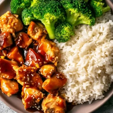 Plate of cozy Asian-style teriyaki chicken garnished with sesame seeds and green onions.