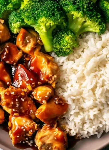 Plate of cozy Asian-style teriyaki chicken garnished with sesame seeds and green onions.