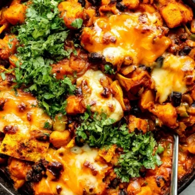 Cozy butternut squash and black bean enchiladas cooked in a skillet
