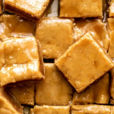 Cozy maple blondies topped with a delicious maple glaze on a wooden table