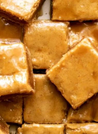 Cozy maple blondies topped with a delicious maple glaze on a wooden table