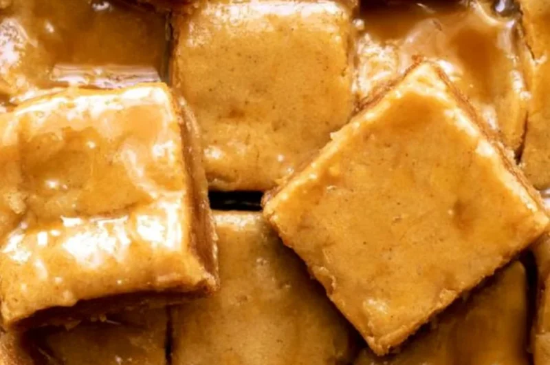 Cozy maple blondies topped with a delicious maple glaze on a wooden table