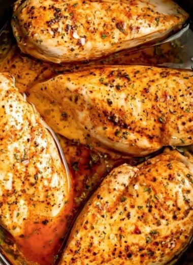 Slow cooker chicken breasts served on a plate, garnished with herbs.