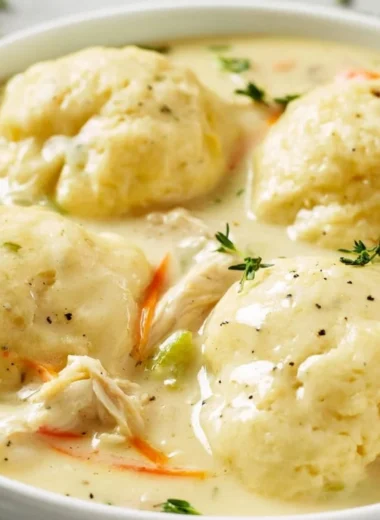Bowl of homemade chicken and dumplings served with fresh herbs