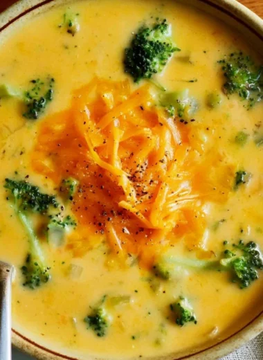 Delicious bowl of easy broccoli cheddar soup topped with cheese and herbs