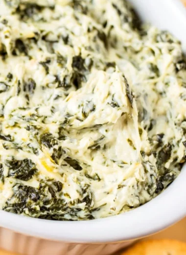 Easy hot spinach dip served in a bowl with chips and veggies.