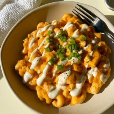 High protein buffalo chicken pasta topped with fresh herbs and cheese
