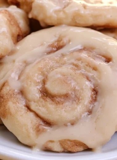 Delicious soft cinnamon roll cookies topped with icing on a wooden table.